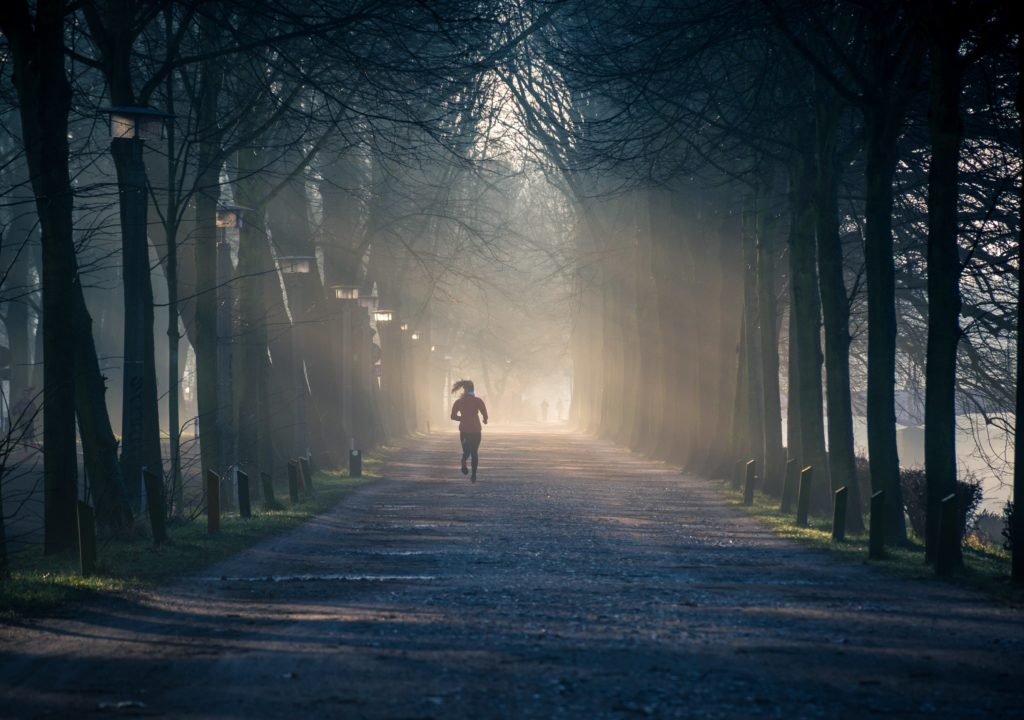 Woman running in a trail during sunrise showing the powerful Benefits of Regular Exercise